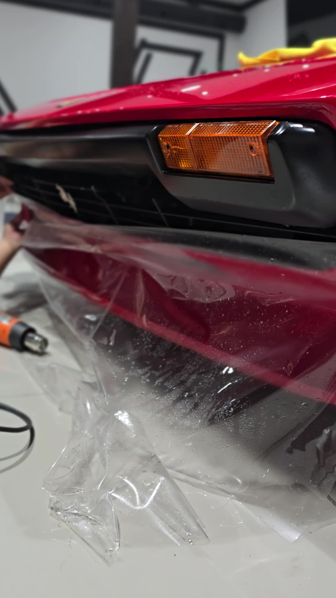 Clear paint protection film being fitted to the front of a red Ferrari